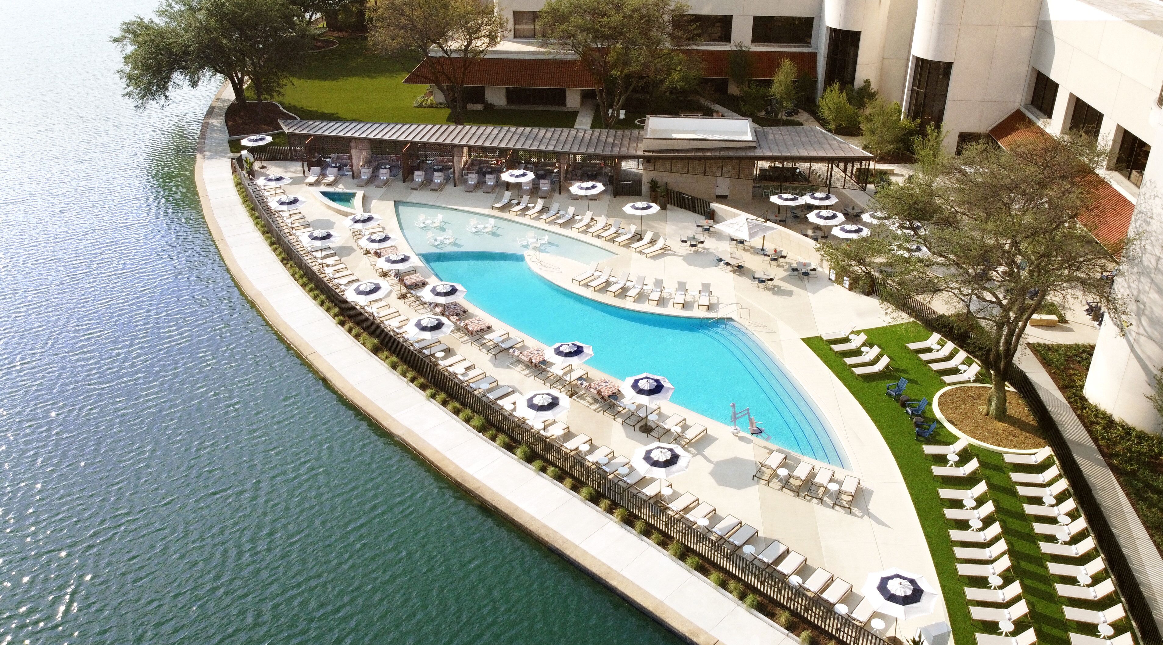 Omni Las Colinas pool deck with umbrellas and landscaped surroundings